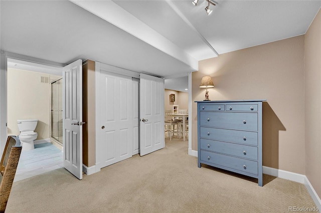 bedroom featuring connected bathroom and light colored carpet