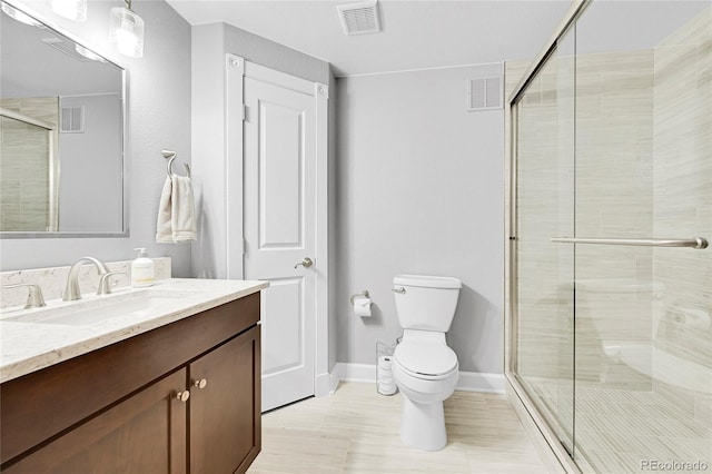 bathroom featuring a shower with door, vanity, and toilet