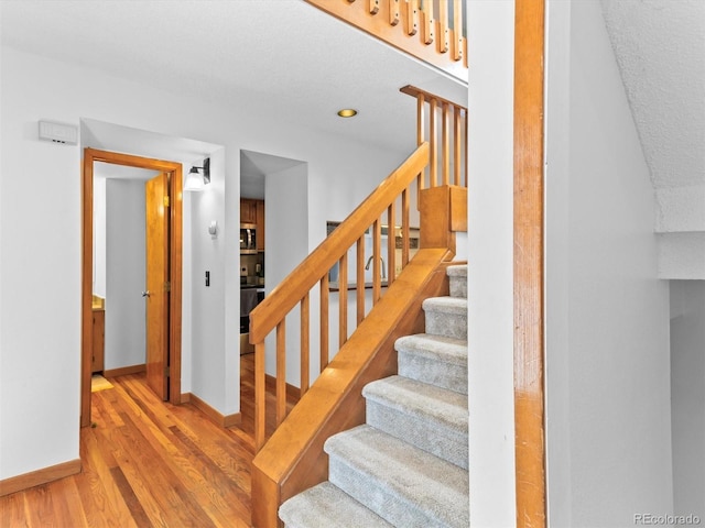 staircase with hardwood / wood-style floors and sink