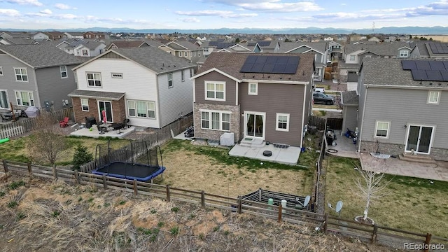 rear view of property with a patio area, a fenced backyard, solar panels, and a residential view