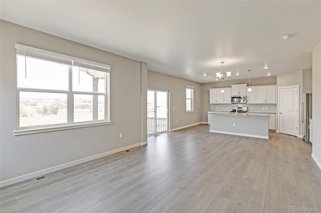 unfurnished living room with a chandelier and light hardwood / wood-style flooring