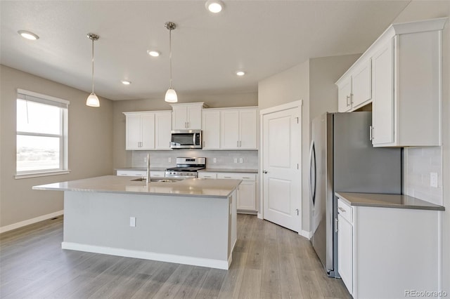 kitchen with white cabinetry, sink, hanging light fixtures, stainless steel appliances, and tasteful backsplash