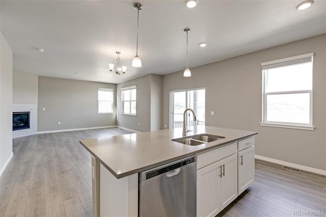 kitchen featuring white cabinetry, dishwasher, sink, pendant lighting, and a kitchen island with sink