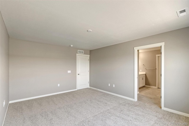 unfurnished bedroom featuring ensuite bath and light colored carpet