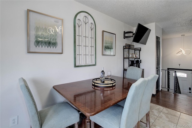 tiled dining room featuring a textured ceiling