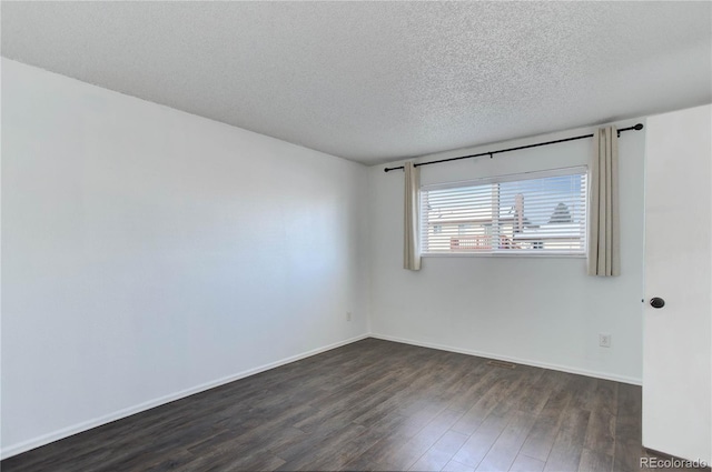 spare room with a textured ceiling and dark hardwood / wood-style floors