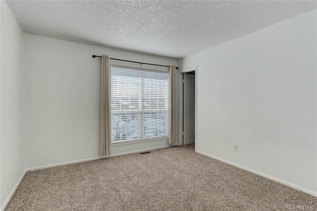 spare room featuring carpet and a textured ceiling