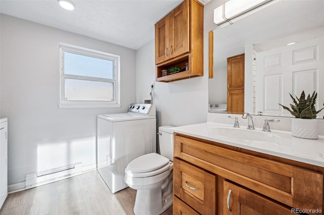 bathroom with wood-type flooring, washer / dryer, vanity, a baseboard heating unit, and toilet