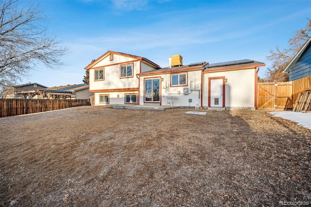 rear view of property featuring solar panels