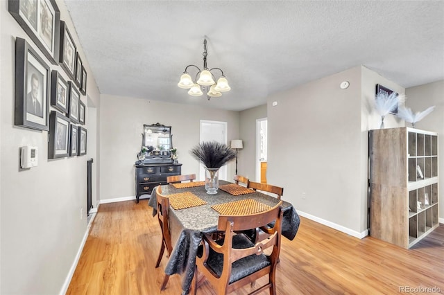 313 E Grant Ave, Fowler, CO 81039 - dining room with a chandelier, light wood-style floors, baseboards, and a textured ceiling