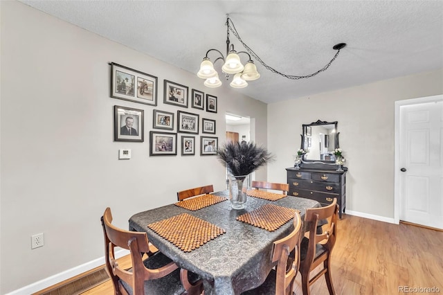 313 E Grant Ave, Fowler, CO 81039 - dining space featuring a chandelier, baseboards, light wood-style flooring, and a textured ceiling