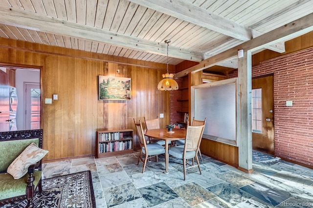 dining space with wood ceiling, beamed ceiling, wood walls, and stone tile floors