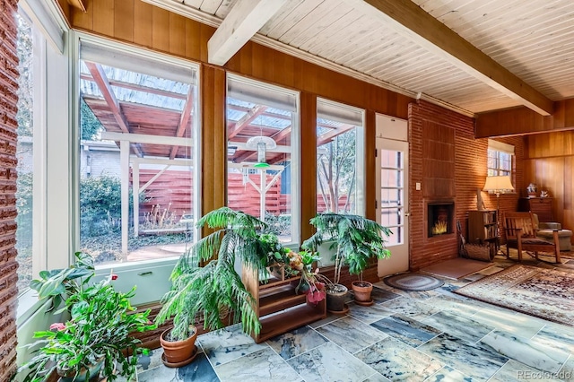 sunroom featuring a brick fireplace, beam ceiling, and wooden ceiling