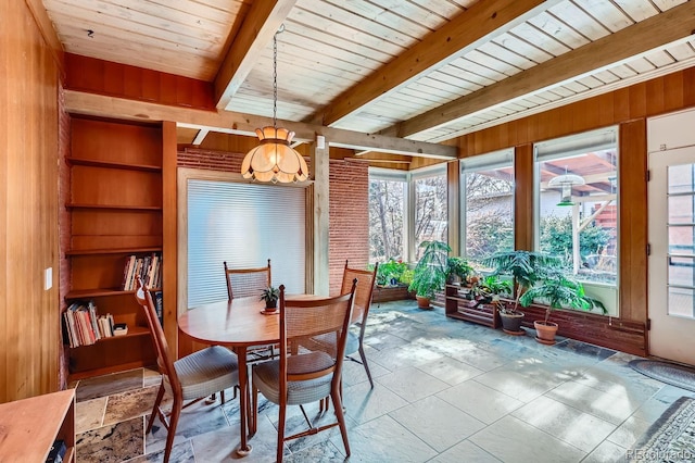 dining space with stone tile flooring, wood walls, wood ceiling, and beam ceiling