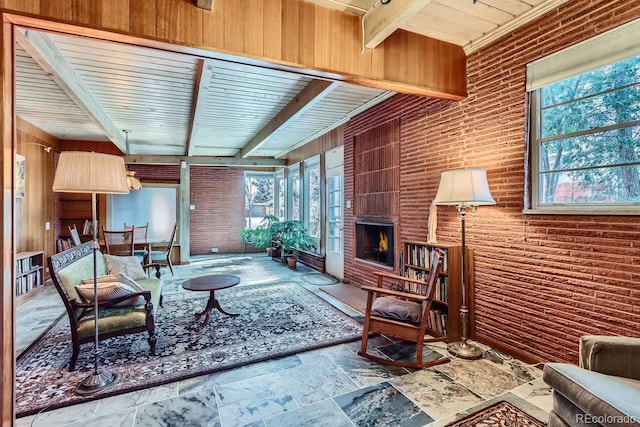 sunroom / solarium featuring a large fireplace, beam ceiling, and a wealth of natural light