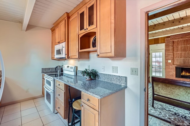 kitchen featuring white microwave, a fireplace, beam ceiling, double oven range, and dark stone countertops