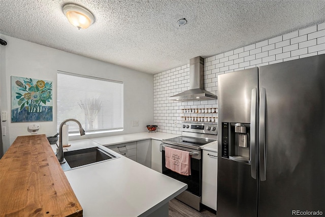 kitchen featuring gray cabinets, sink, wooden counters, stainless steel appliances, and wall chimney exhaust hood