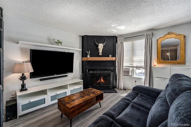 living room with hardwood / wood-style floors, a large fireplace, and a textured ceiling