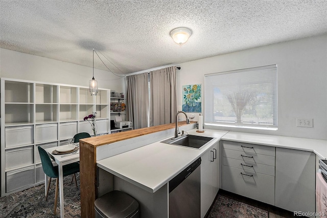 kitchen with sink, hanging light fixtures, a textured ceiling, stainless steel dishwasher, and kitchen peninsula