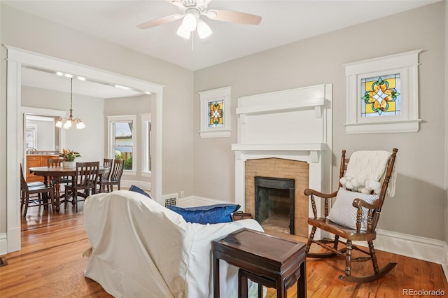 2360 S Milwaukee St, Denver, CO 80210 - living area featuring a brick fireplace, ceiling fan, light wood finished floors, and a chandelier