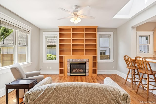 2360 S Milwaukee St, Denver, CO 80210 - living area with wood finished floors, a tiled fireplace, a ceiling fan, and a skylight