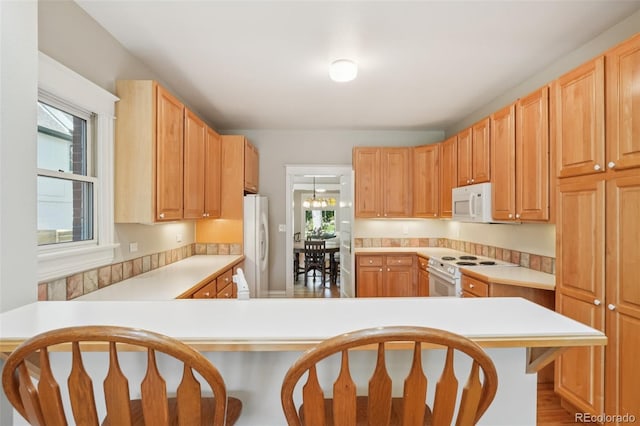 2360 S Milwaukee St, Denver, CO 80210 - kitchen featuring white appliances, a breakfast bar, light countertops, and a peninsula