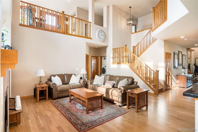 living room with light hardwood / wood-style flooring, a healthy amount of sunlight, and a high ceiling