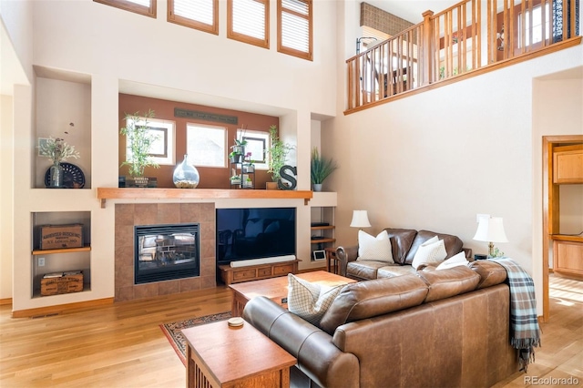 living room with a fireplace, a high ceiling, and light hardwood / wood-style flooring