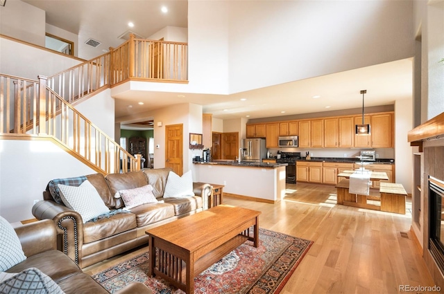 living room with light hardwood / wood-style floors, high vaulted ceiling, and a tiled fireplace