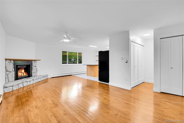 26752 Vosler St, Conifer, CO 80433 - unfurnished living room with a baseboard radiator, ceiling fan, a stone fireplace, light wood-type flooring, and baseboards