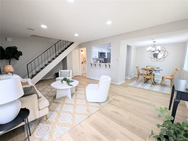 living area featuring stairs, recessed lighting, light wood finished floors, and a chandelier