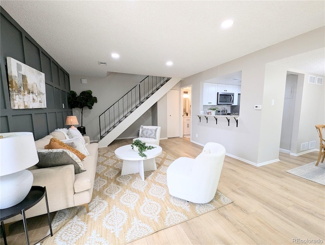 living area with visible vents, recessed lighting, light wood-style floors, baseboards, and stairs