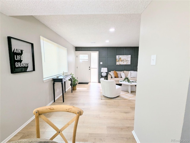 corridor with light wood-style flooring, recessed lighting, baseboards, and a textured ceiling