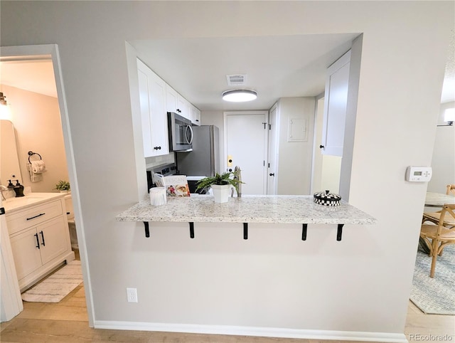 kitchen featuring light wood finished floors, visible vents, appliances with stainless steel finishes, and a kitchen breakfast bar