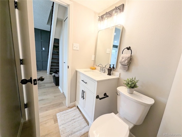 bathroom with toilet, wood finished floors, and vanity