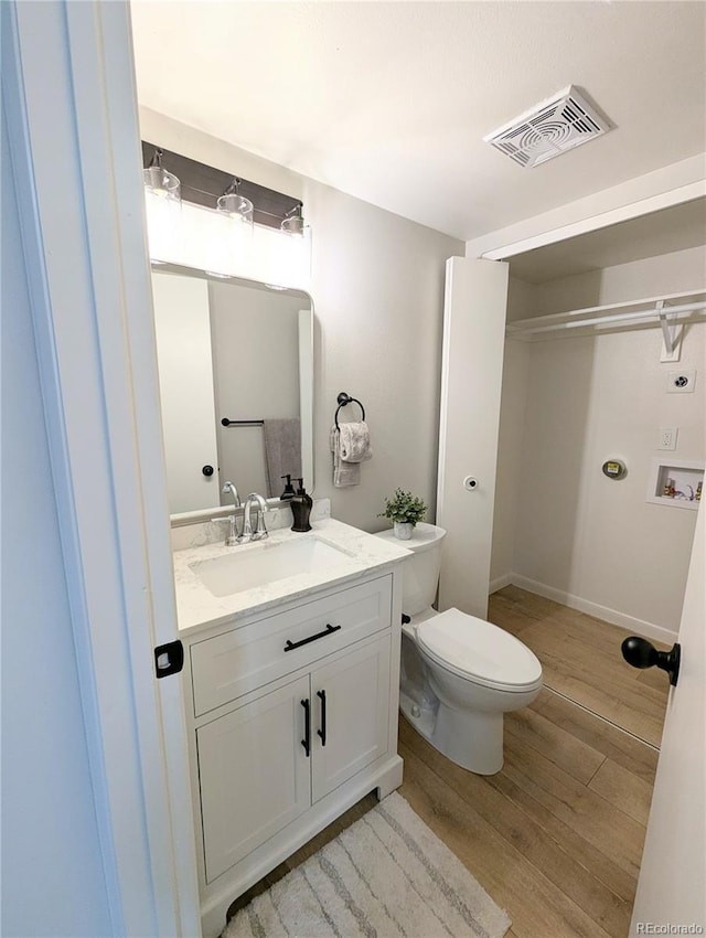 bathroom with vanity, toilet, wood finished floors, and visible vents