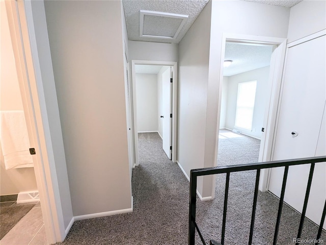 hall featuring baseboards, carpet floors, and a textured ceiling