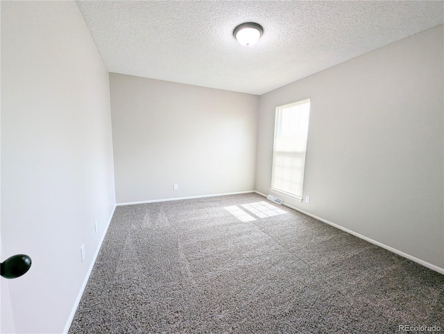 empty room featuring visible vents, carpet floors, a textured ceiling, and baseboards