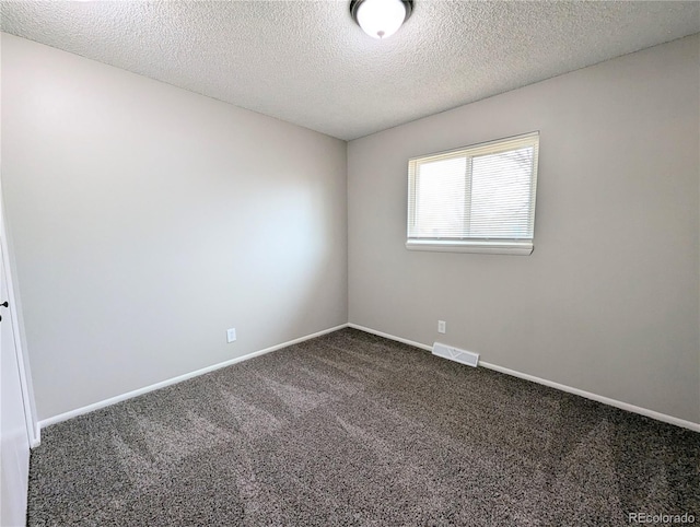 spare room with visible vents, baseboards, a textured ceiling, and dark carpet