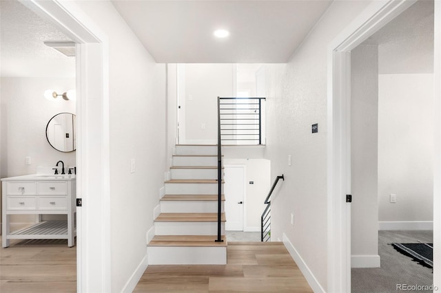 stairs with sink and carpet flooring