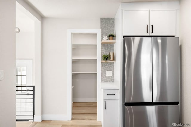 interior space featuring white cabinetry, light hardwood / wood-style flooring, and stainless steel refrigerator