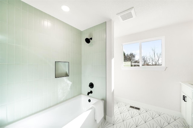 bathroom featuring tiled shower / bath combo and vanity