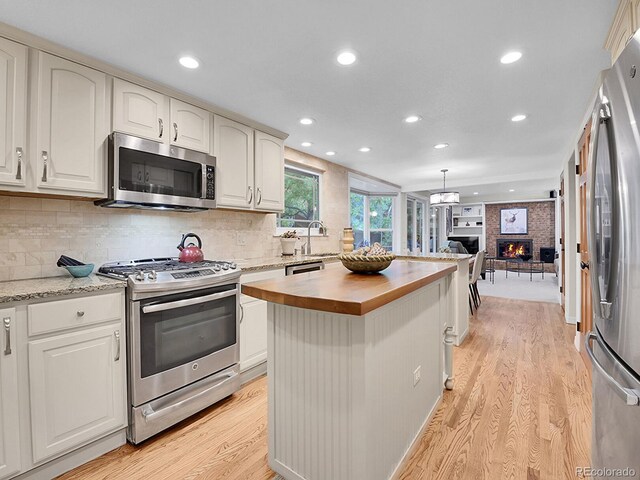 7030 S Fillmore Ct, Centennial, CO 80122 - kitchen featuring appliances with stainless steel finishes, butcher block counters, light wood-style floors, recessed lighting, and a fireplace