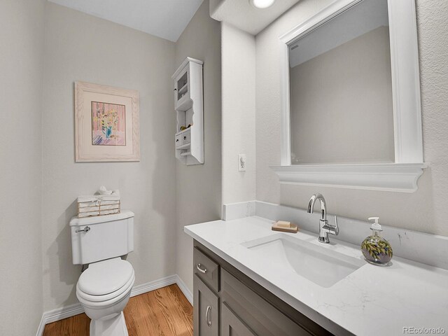 7030 S Fillmore Ct, Centennial, CO 80122 - half bathroom featuring wood finished floors, toilet, vanity, and baseboards
