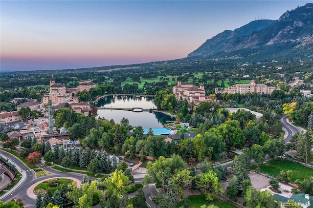 aerial view at dusk featuring a water and mountain view