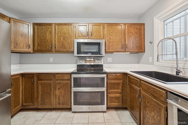 kitchen with sink, light tile patterned floors, and appliances with stainless steel finishes