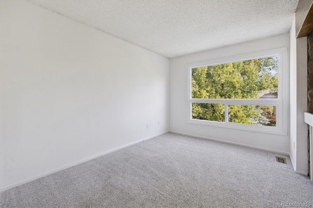 carpeted empty room featuring a textured ceiling