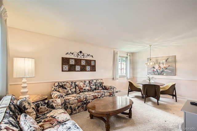 living room featuring baseboards, a notable chandelier, and carpet flooring