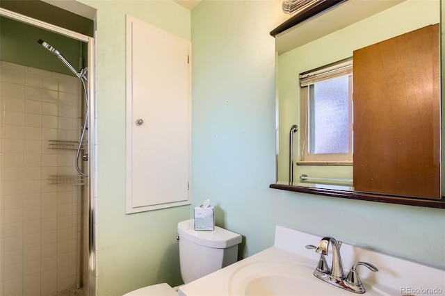 bathroom featuring toilet, vanity, and tiled shower