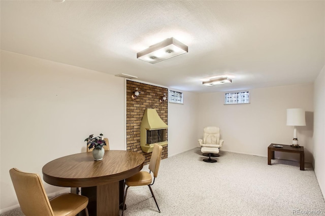 dining area with a brick fireplace, carpet, and a textured ceiling